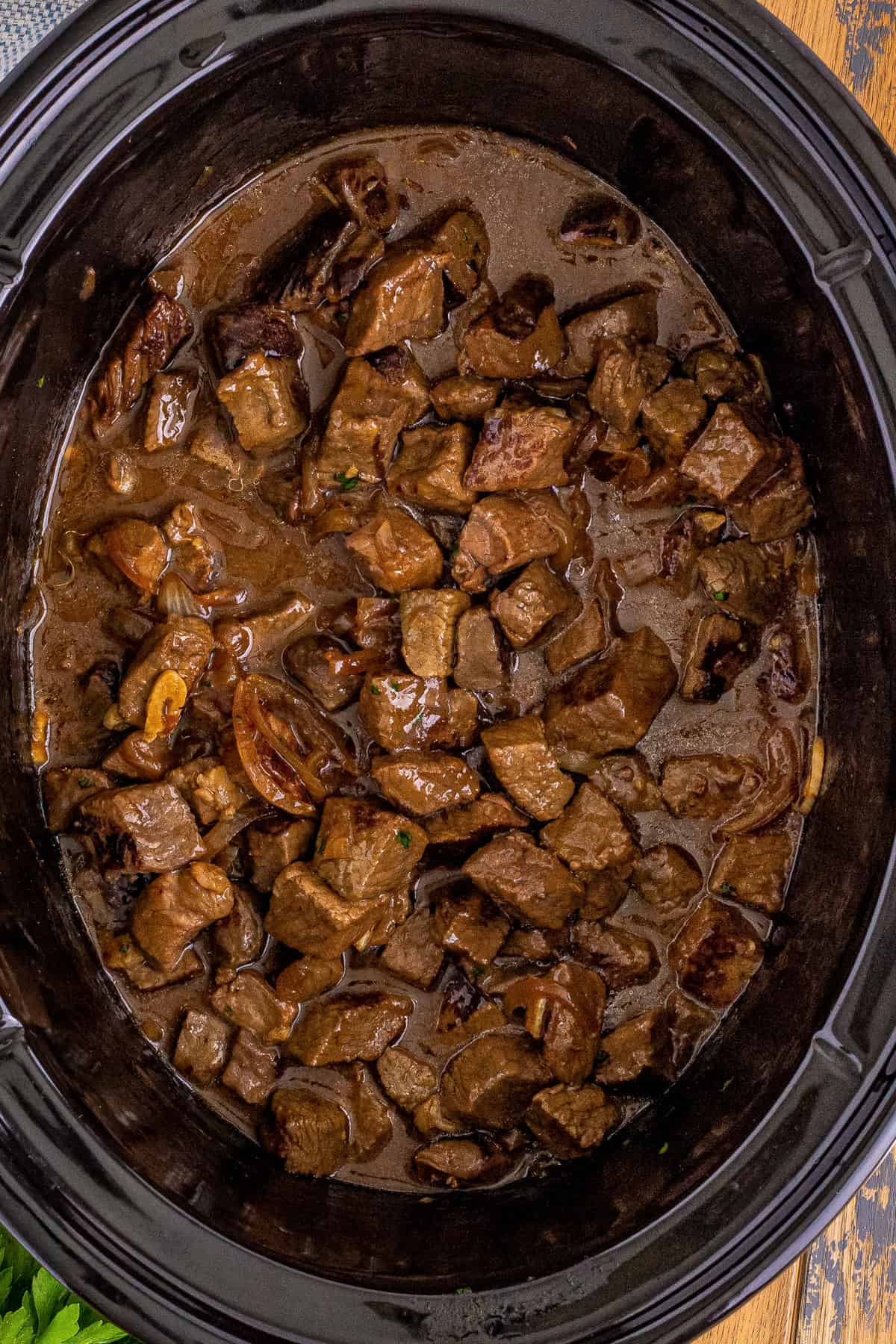 Crockpot steak bites in au jus sauce with garlic and sweet onions.