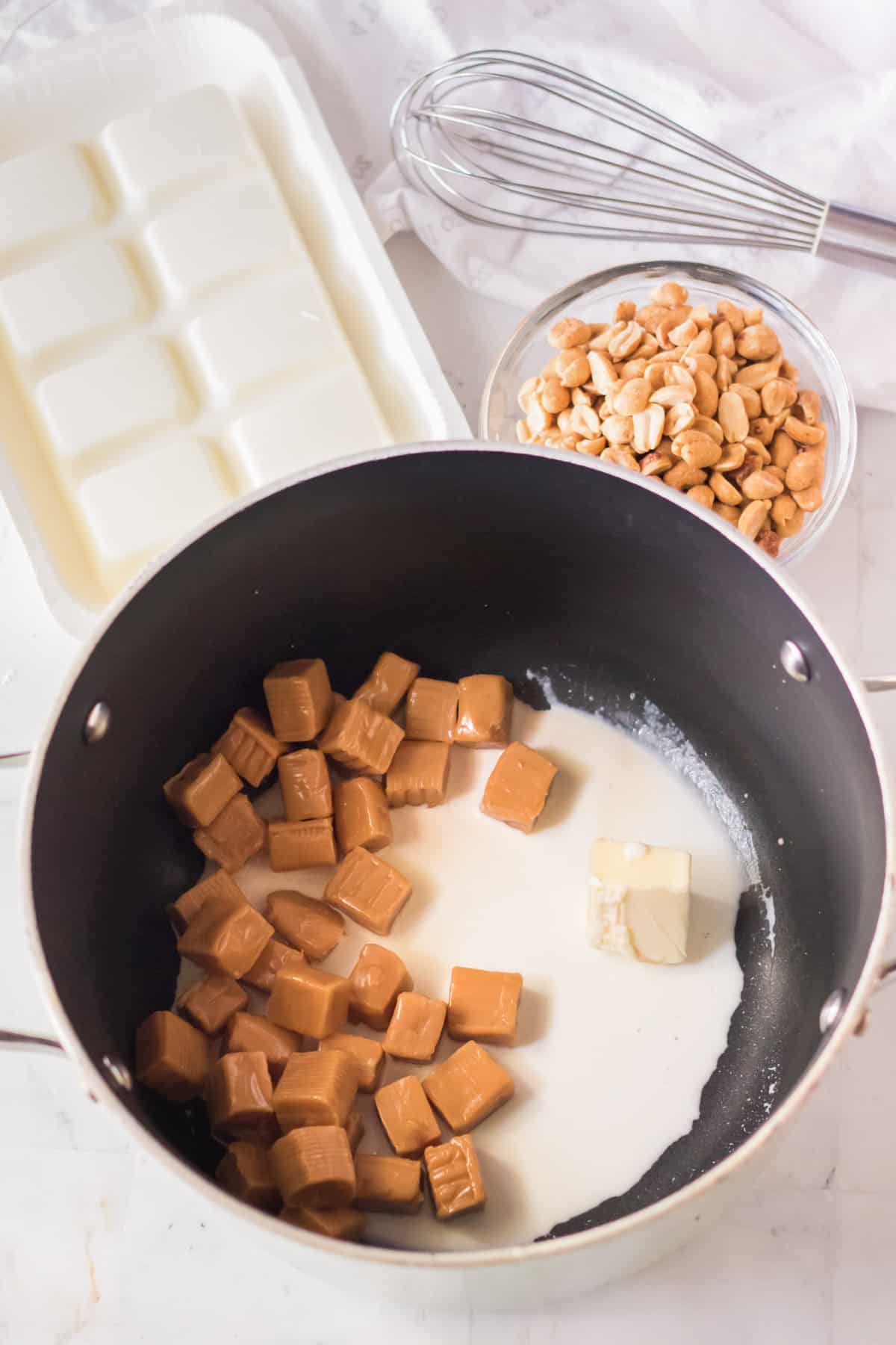 Unwrapped caramels, cream, and butter in saucepan.