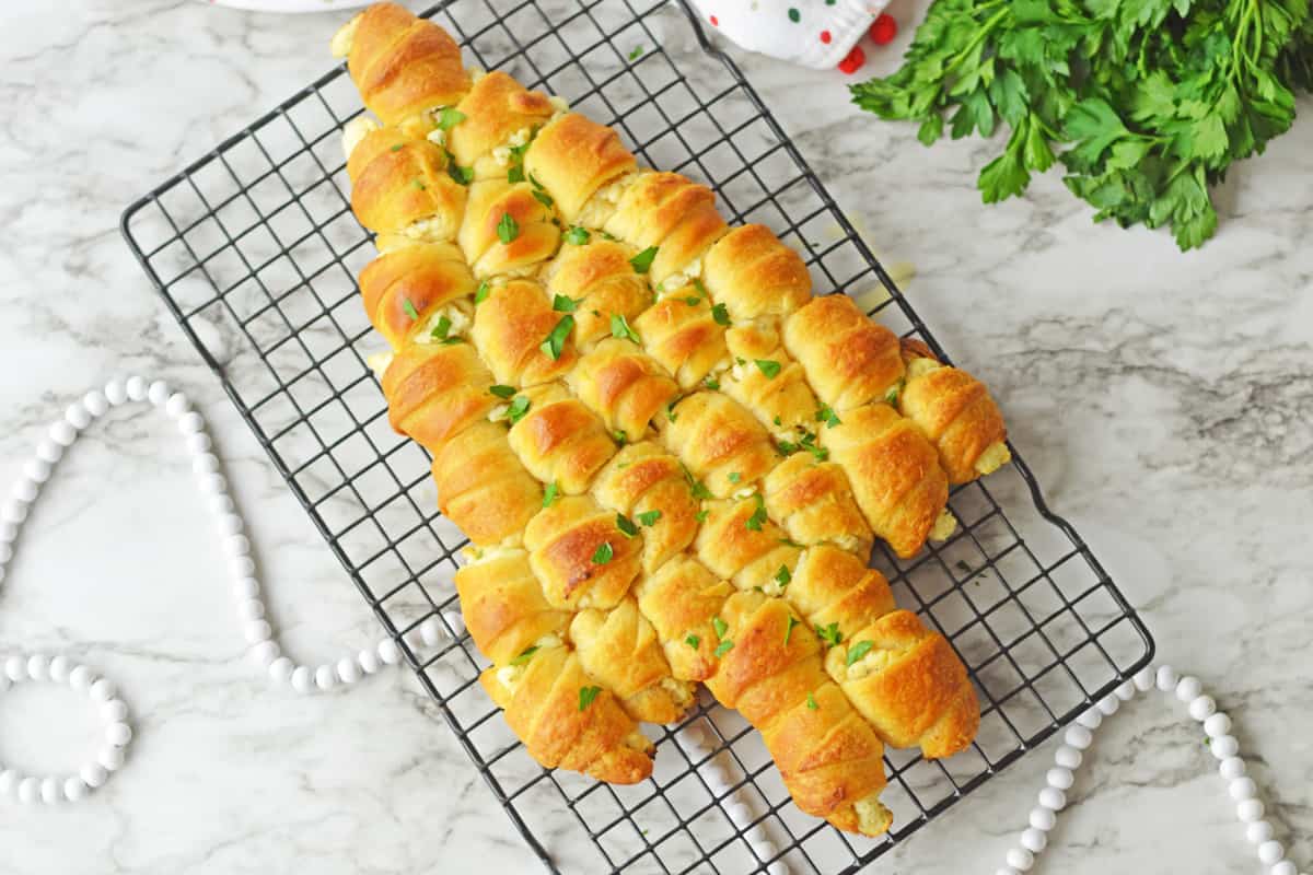 Christmas appetizer made of cheese-stuffed crescents baked in tree shape and topped with butter and parsley.