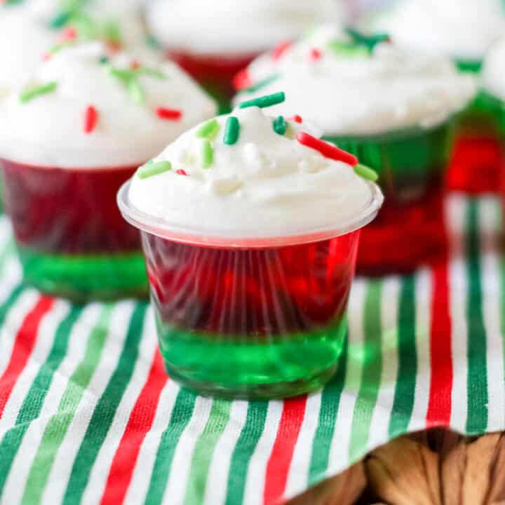 Christmas Jello Shots with layers of red and green jello, whipped cream, and sprinkles.