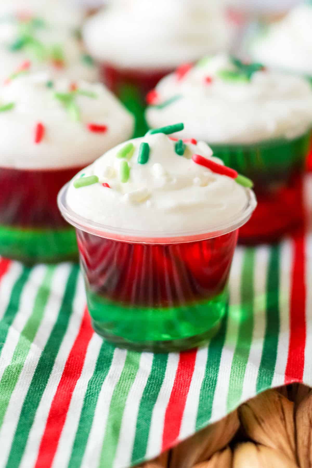 Christmas Jello Shots with layers of red and green jello, whipped cream, and sprinkles.