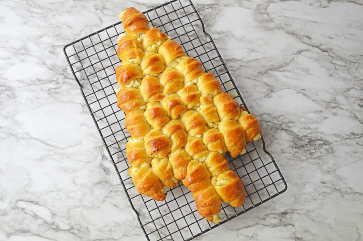 Golden brown crescent roll Christmas tree on wire cooling rack.
