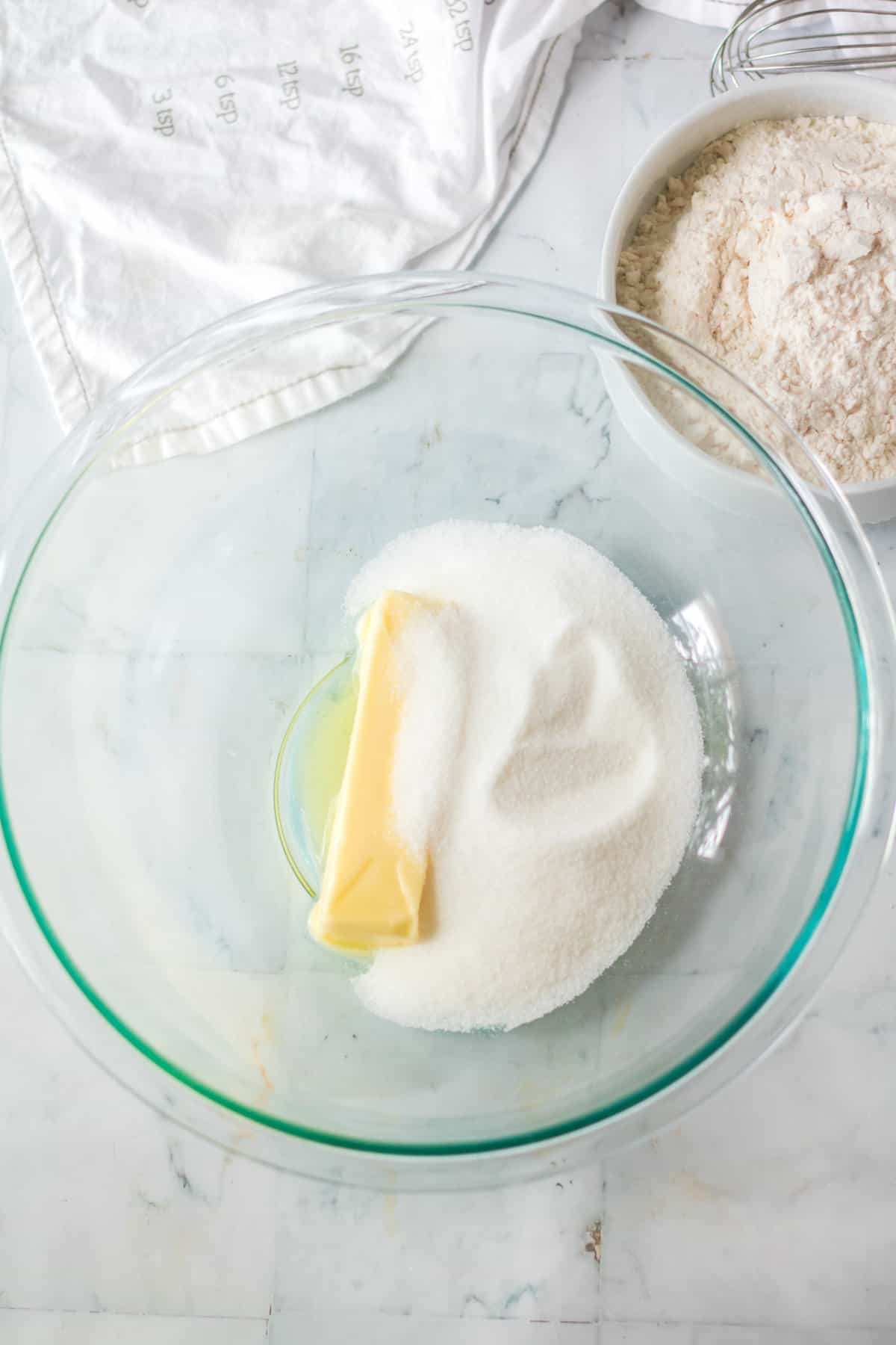 Butter and sugar in a glass mixing bowl.