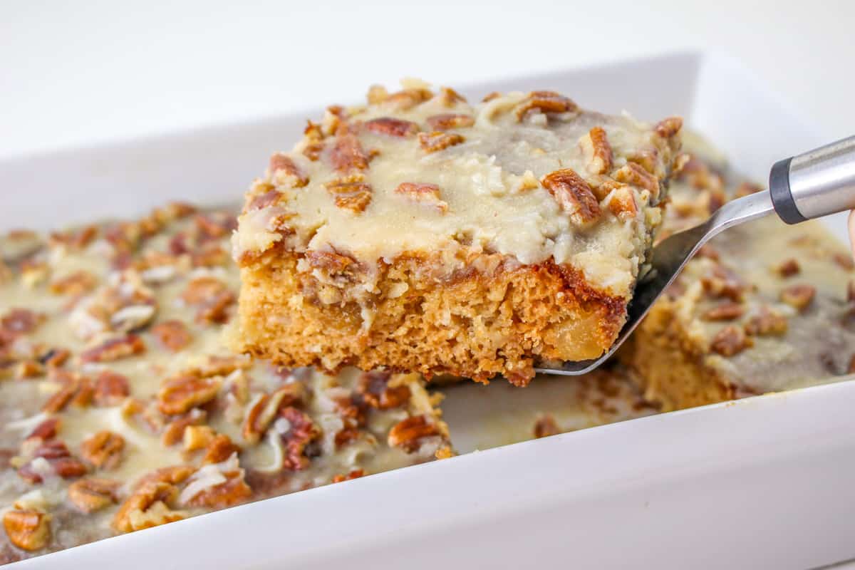 Spatula lifting a square slice of fruit cake out of the pan.