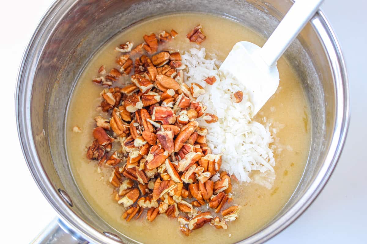 Frosting mixture in sauce pan with shredded coconut and pecans added.