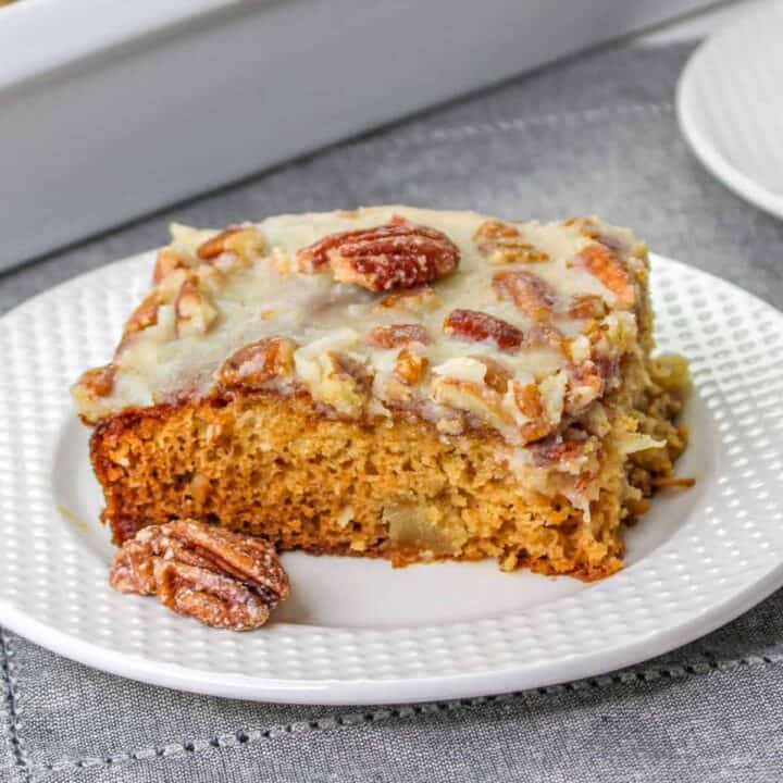 Slice of fruit cocktail cake topped with pecan coconut frosting.