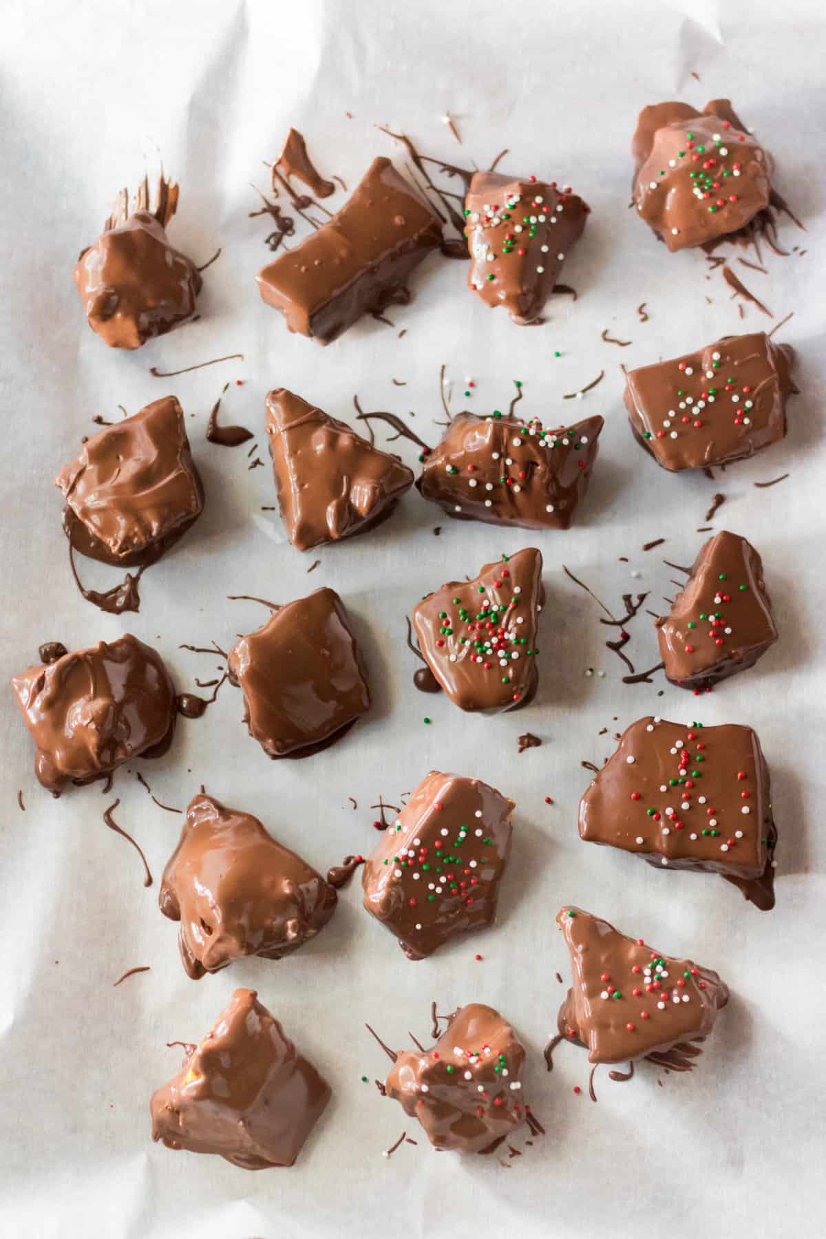 Chocolate covered honeycomb candy pieces on parchment paper.