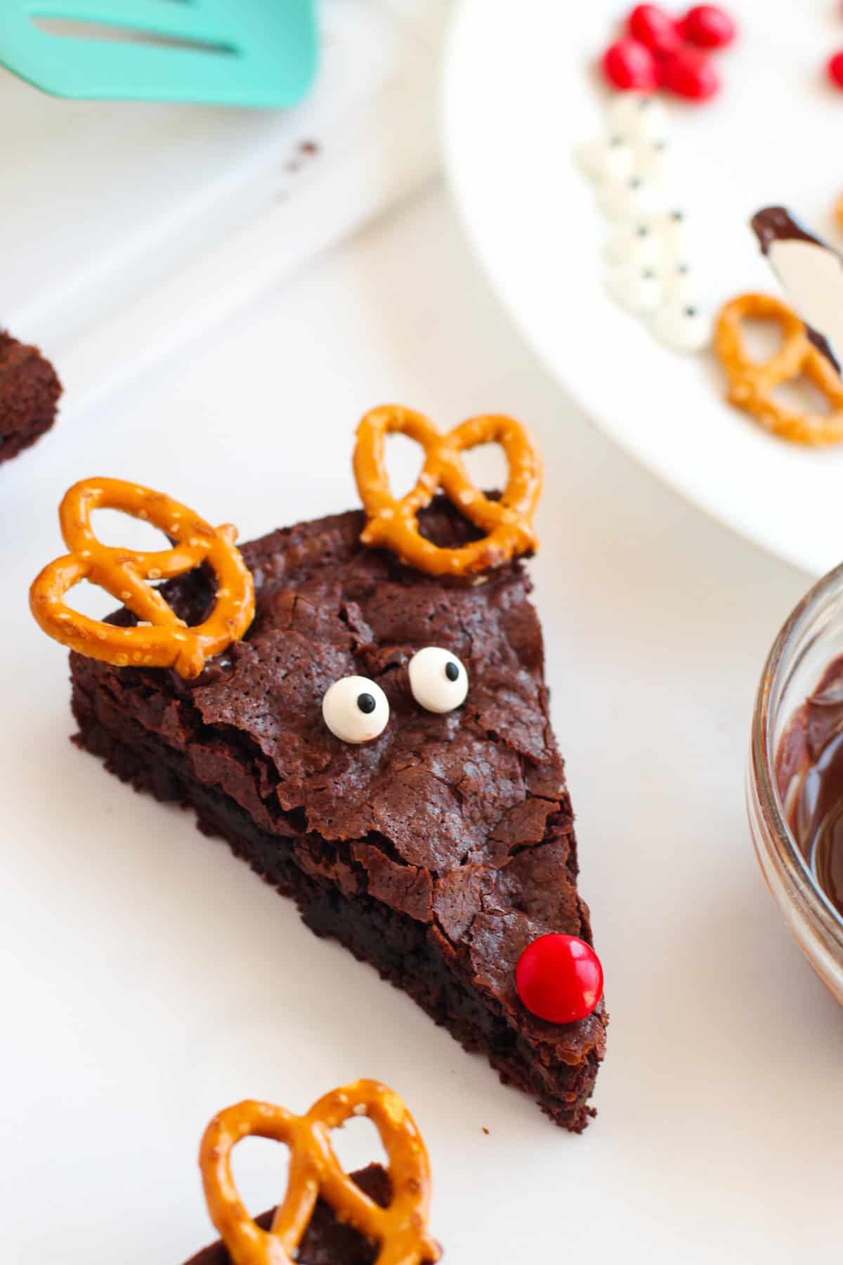 Pretzel twists, candy eyes, and red chocolate candy on brownie to make a reindeer face.