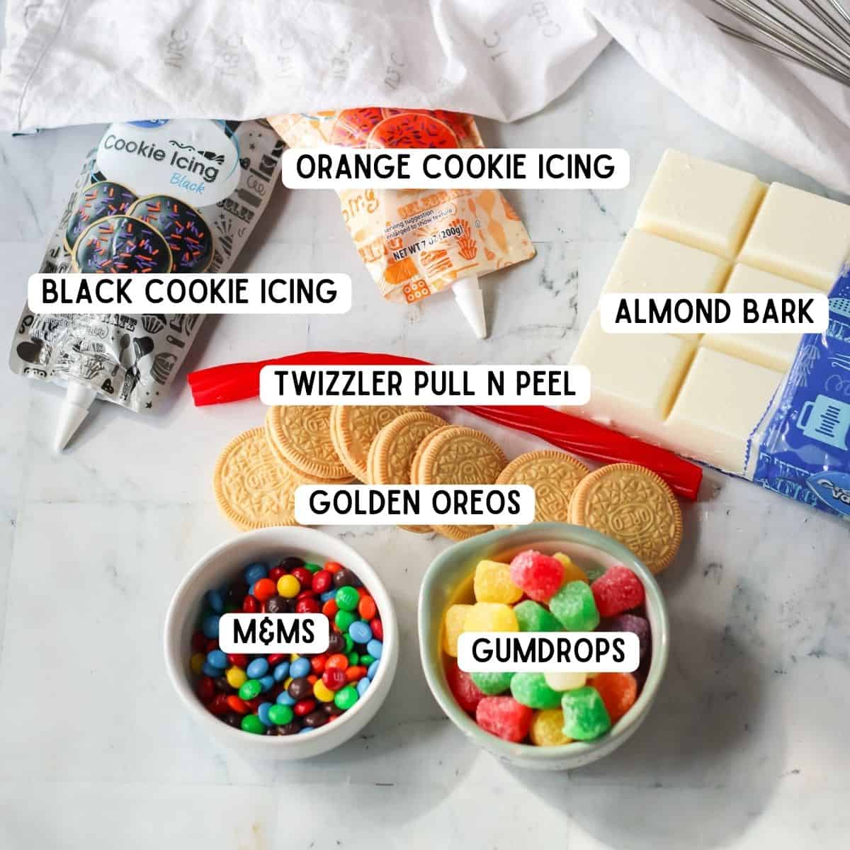Ingredients for snowman bark: black and orange cookie icing, almond bark, golden oreos, gumdrops, M&Ms, twizzler pull and peel candies.