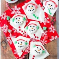 Melted snowman bark with gumdrop earmuffs, mini m&m buttons, and faces drawn on with icing.