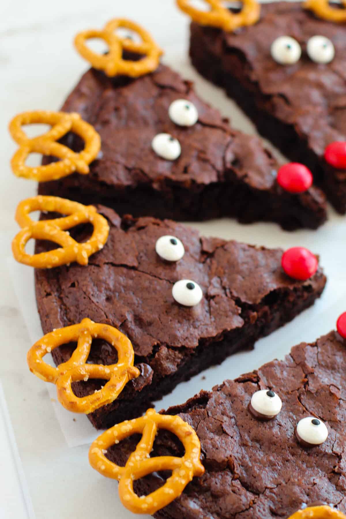 Chocolate brownies decorated with pretzels and candies to look like reindeer.
