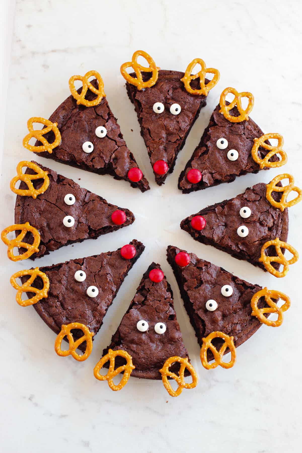 Round pan of brownies sliced into triangles and decorated with reindeer faces.