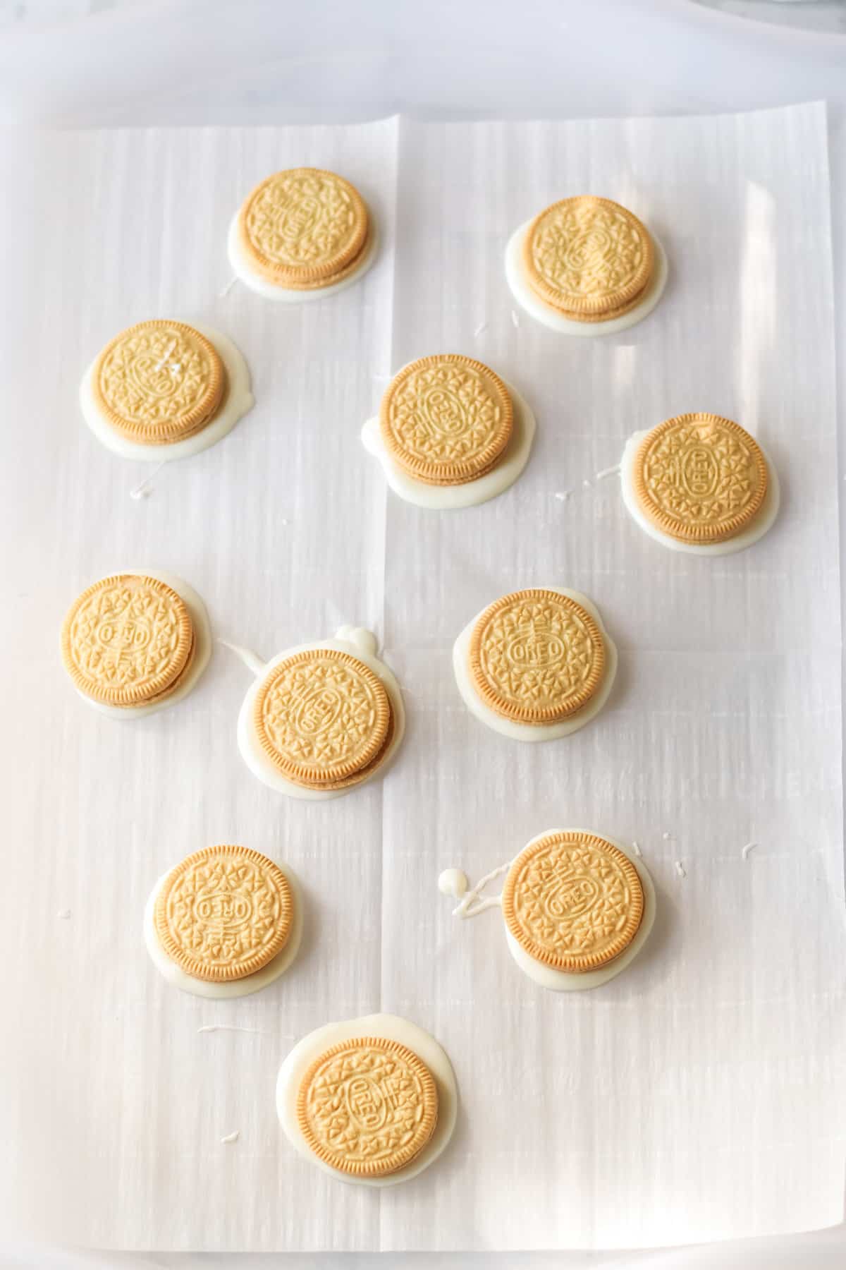 Golden OREO cookies stuck to parchment paper with melted almond bark.