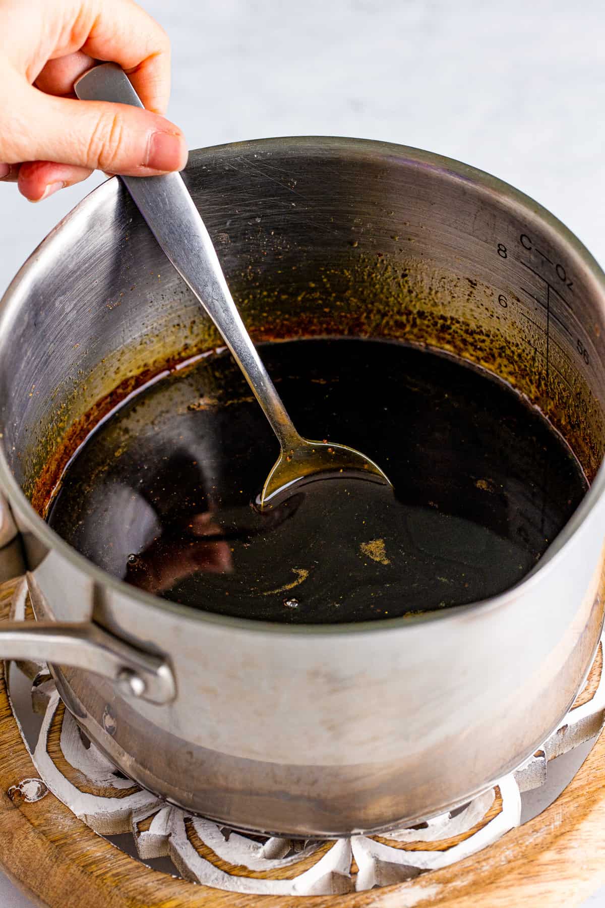 Spoon stirring gingerbread syrup in saucepan.