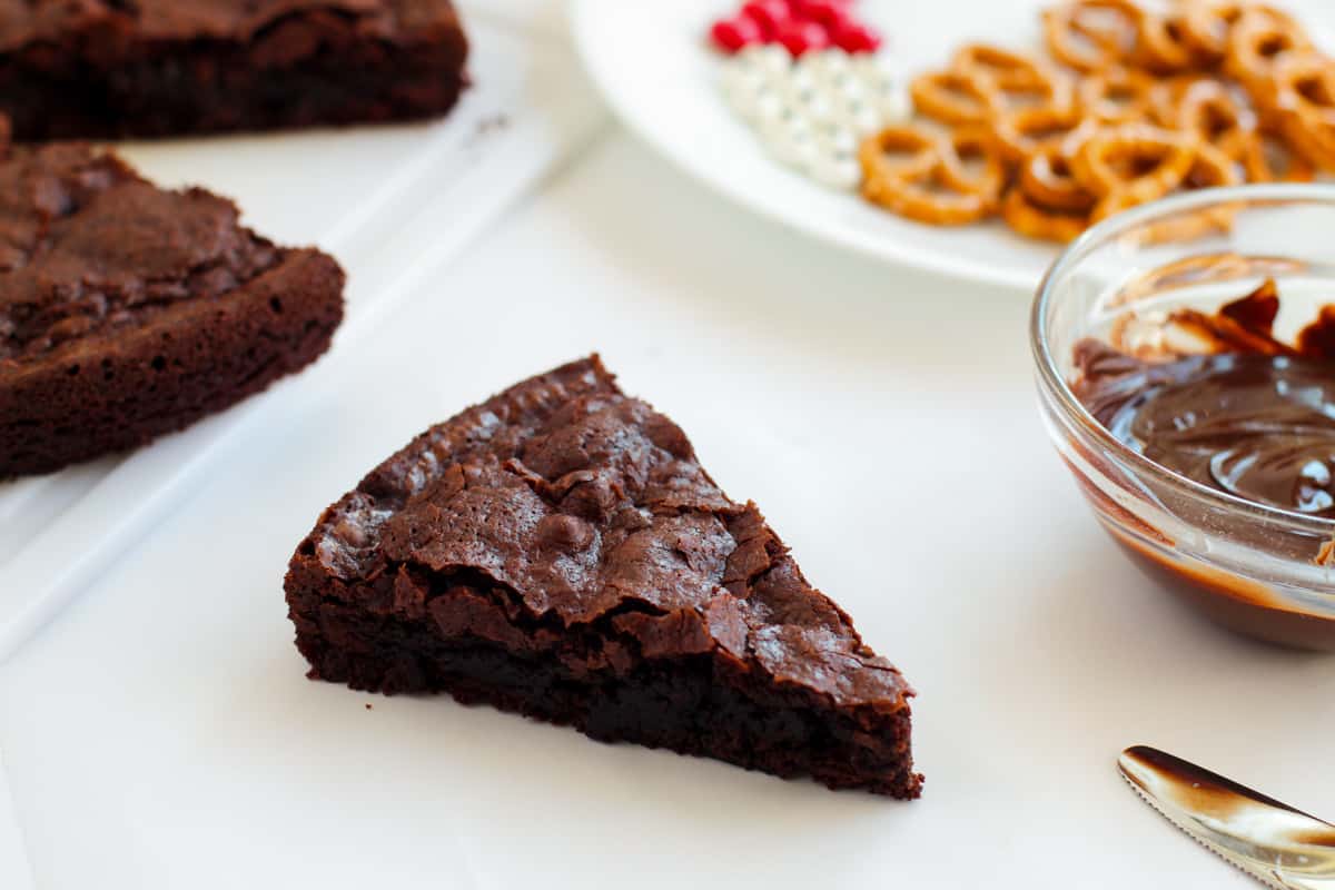 Triangular sliced brownie with remaining brownies and candy decorations in background.