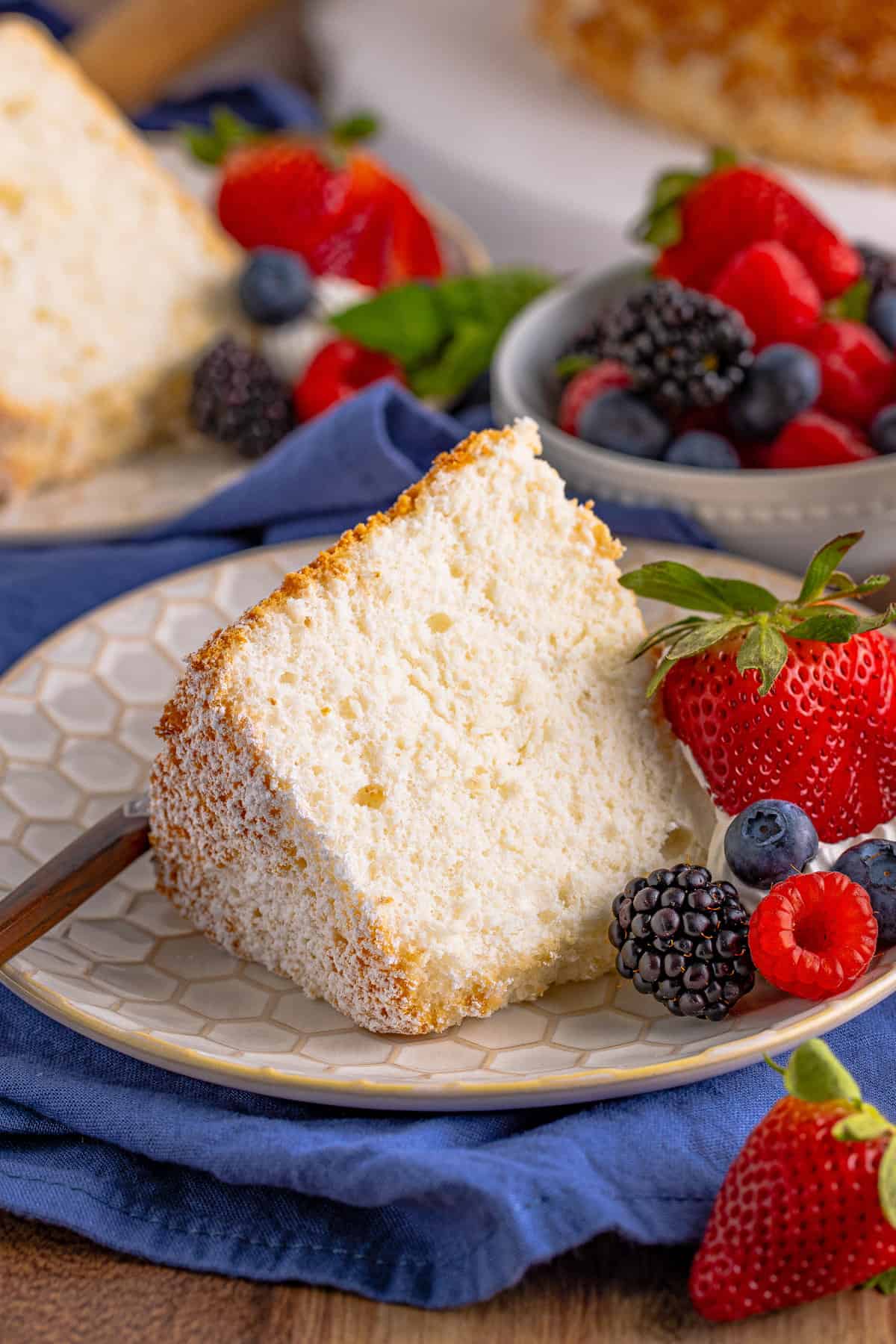 Slice of Angel Food Cake on white plate with fresh berries.