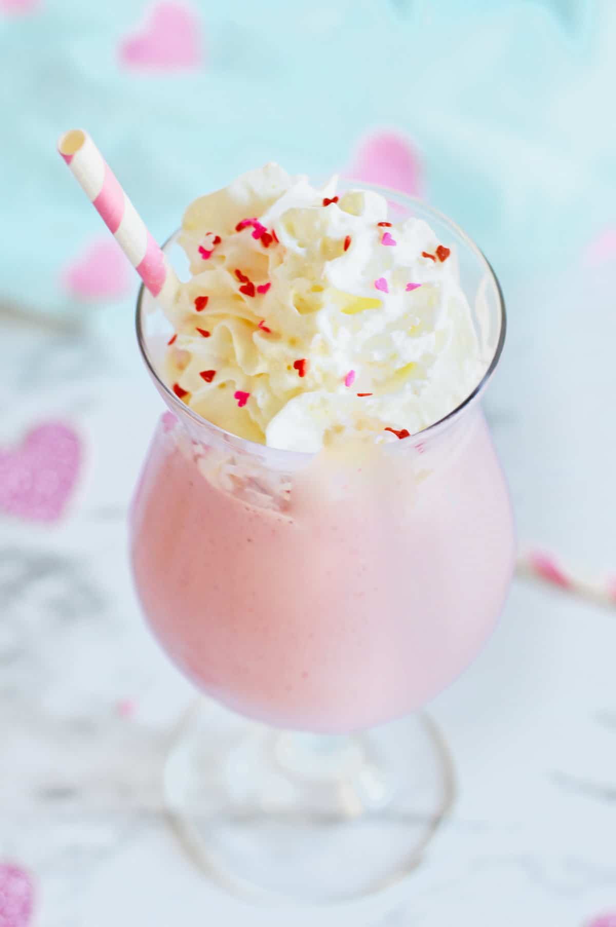 Pink mudslide cocktail with whipped cream and heart shaped sprinkles.