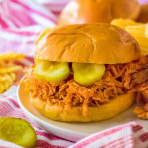 Slow cooker hot honey chicken sandwich served on a soft bun with pickles.