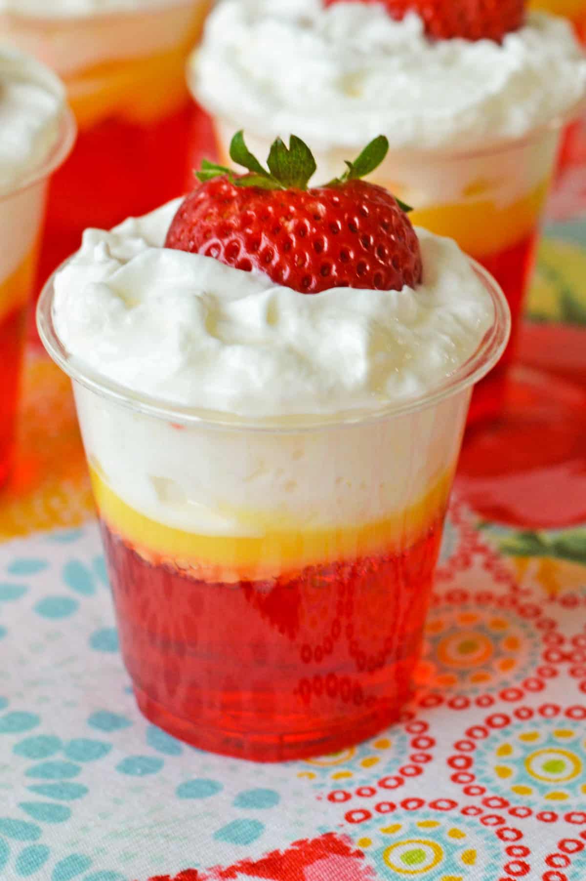 Strawberry and cream vodka jello shots topped with whipped cream and strawberry.