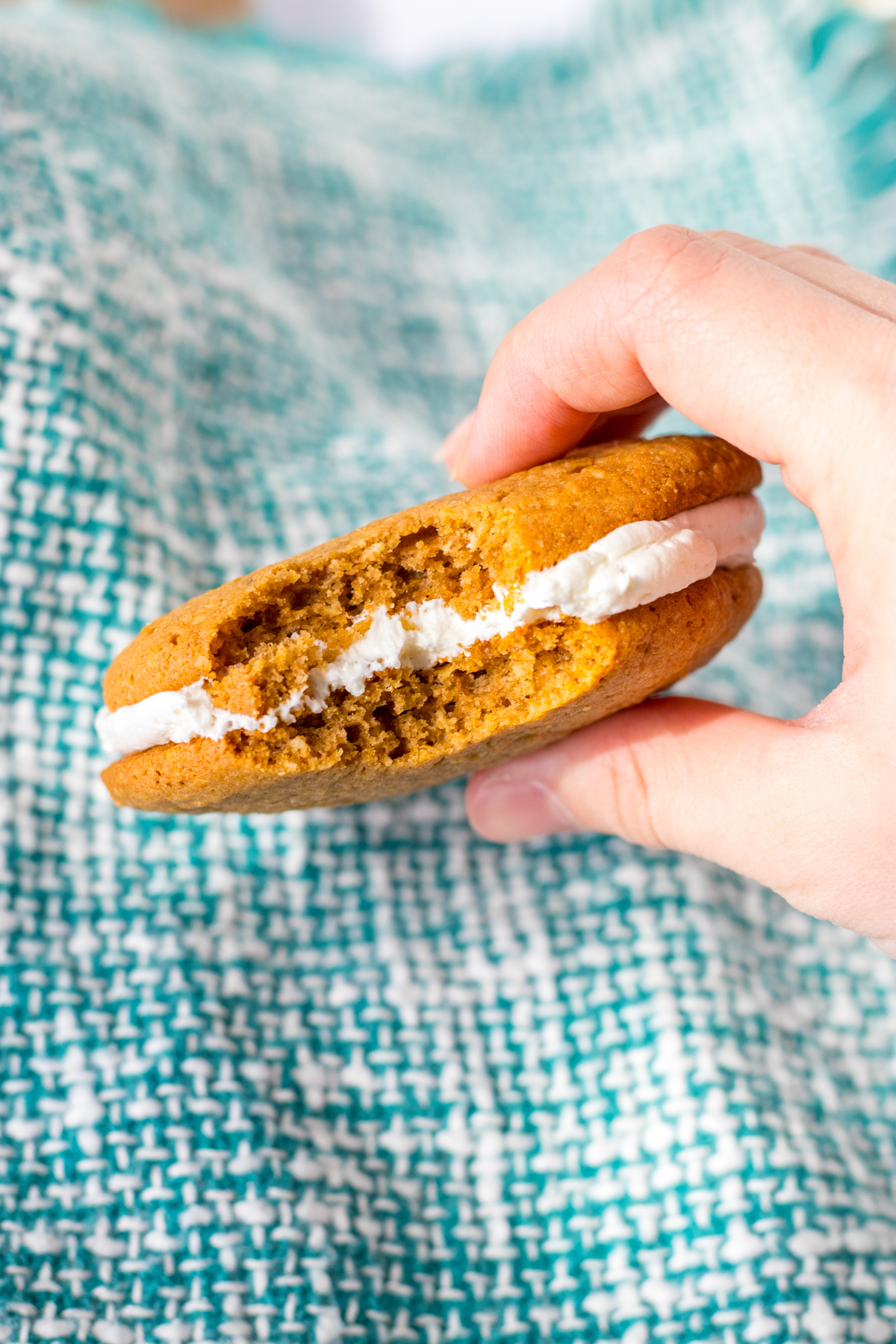 Hand holding large copycat oatmeal cream pie cookie with a bite taken out of it.