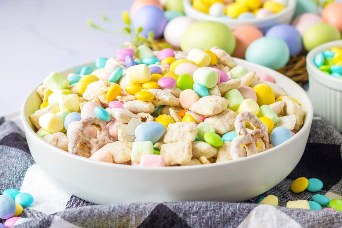 Easter muddy buddy snack mix with funfetti coated rice chex, pretzels, mini eggs, mini marshmallows, and pastel sprinkles and m&ms.