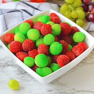 Candied grapes made with red and green jello powder in a white bowl.
