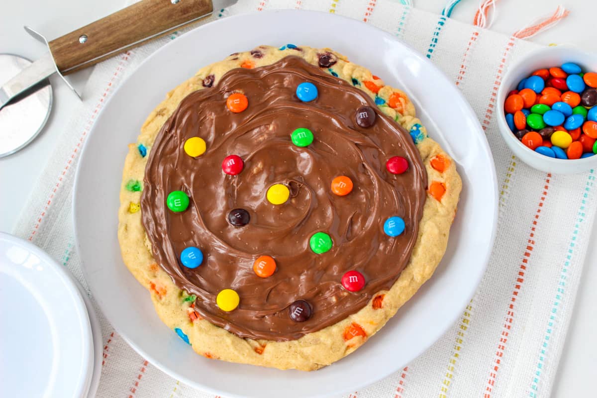 Giant round cookie topped with melted chocolate and M&M candies.