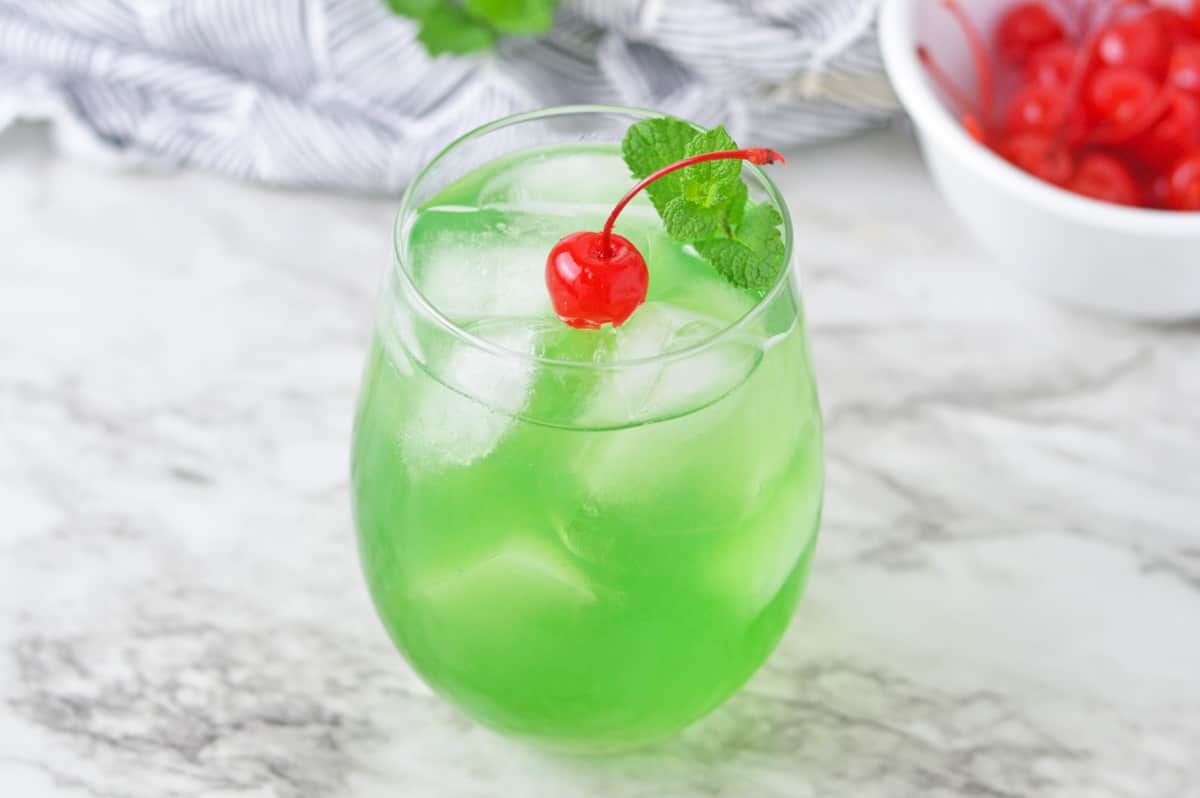 Green drink garnished with cherry and mint.