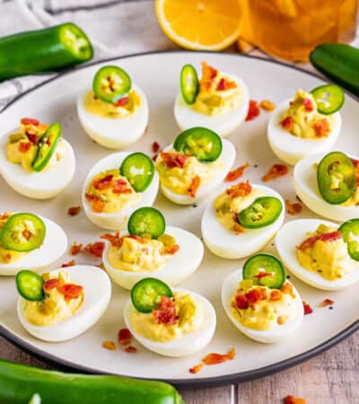 Jalalpeno popper deviled eggs with bacon arranged neatly on a white serving plate.