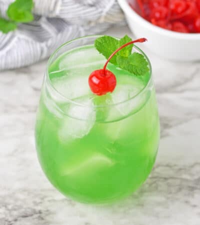 Luck of the Irish green cocktail topped with a cherry and sprig or mint.