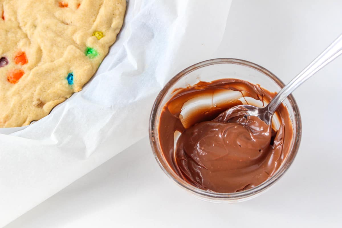 Small bowl of melted chocolate with spoon in it.