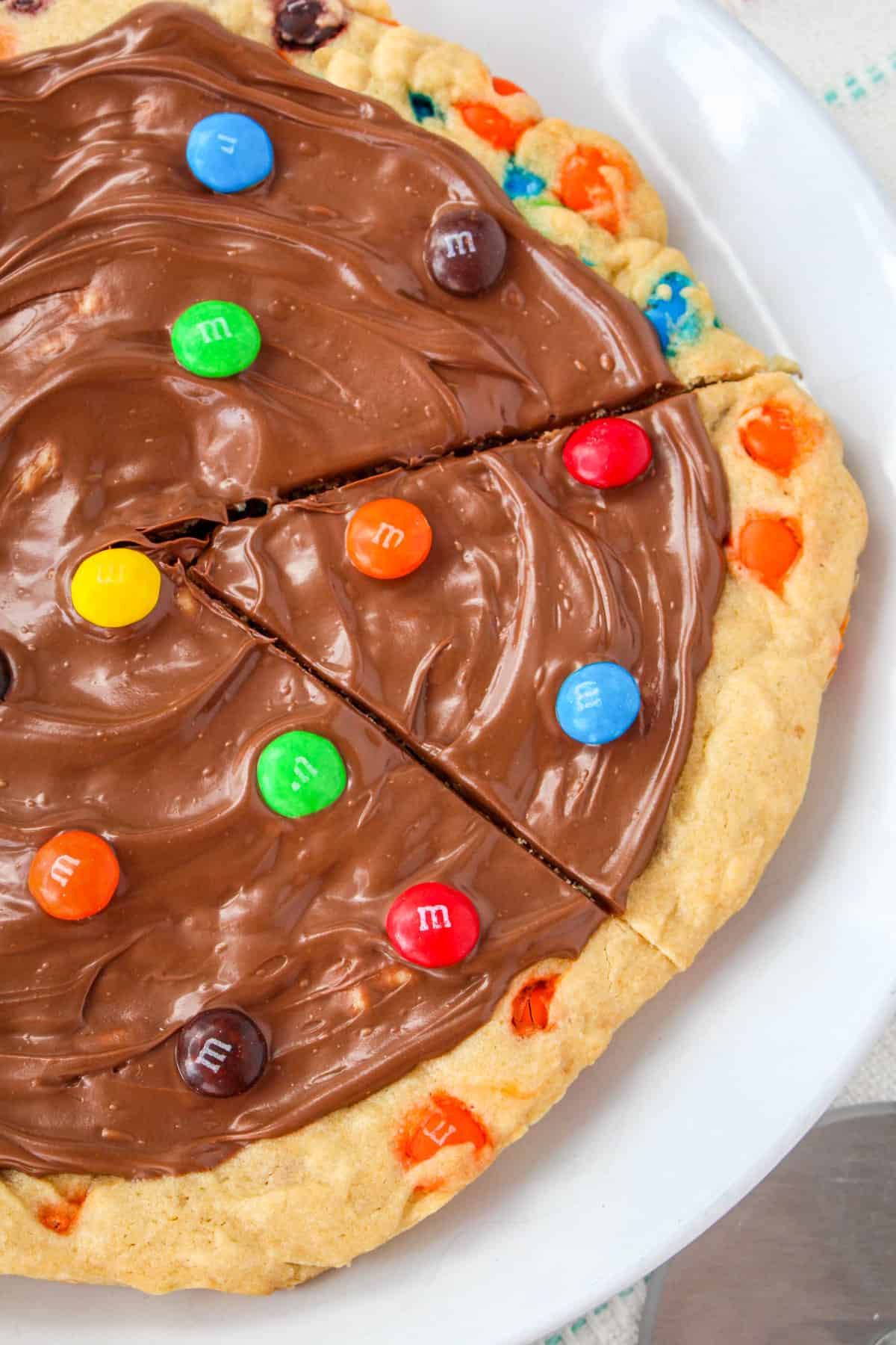 M&M cookie pizza with a triangular slice cut out.