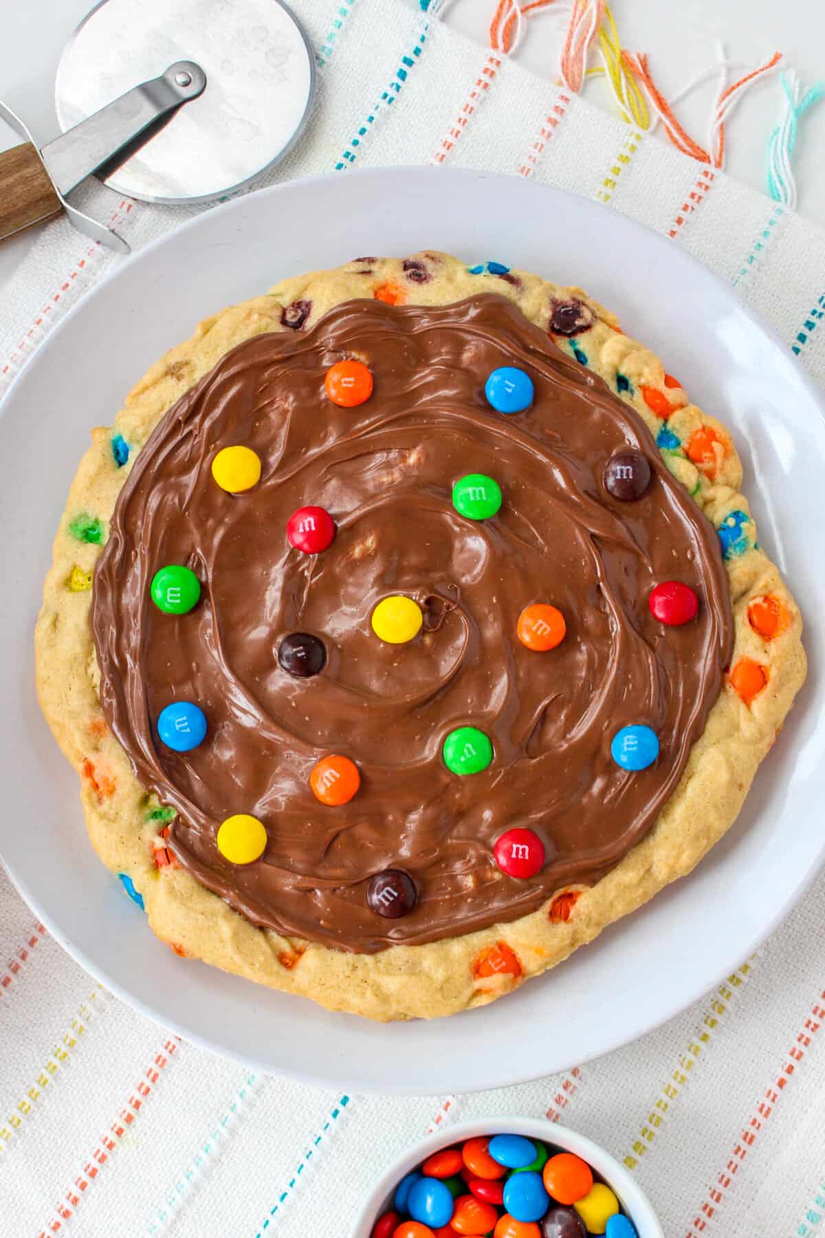 Giant round cookie topped with melted chocolate and M&M candies.