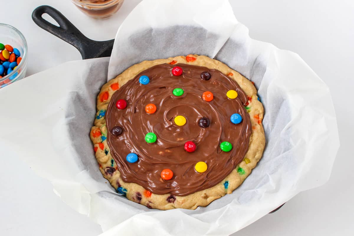 M&Ms pressed into the melted chocolate on top of the skillet cookie.