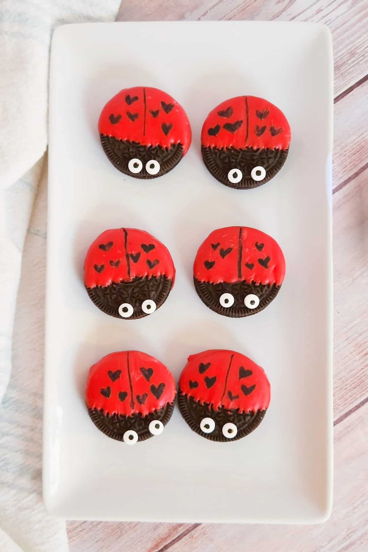 Oreo cookies dipped in red chocolate and decorated  to look like ladybugs with heart spots for Valentine's Day.