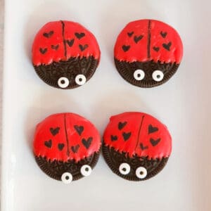 Oreo cookies dipped in red chocolate and decorated to look like ladybugs with heart spots for Valentine's Day.