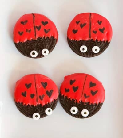 Oreo cookies dipped in red chocolate and decorated to look like ladybugs with heart spots for Valentine's Day.