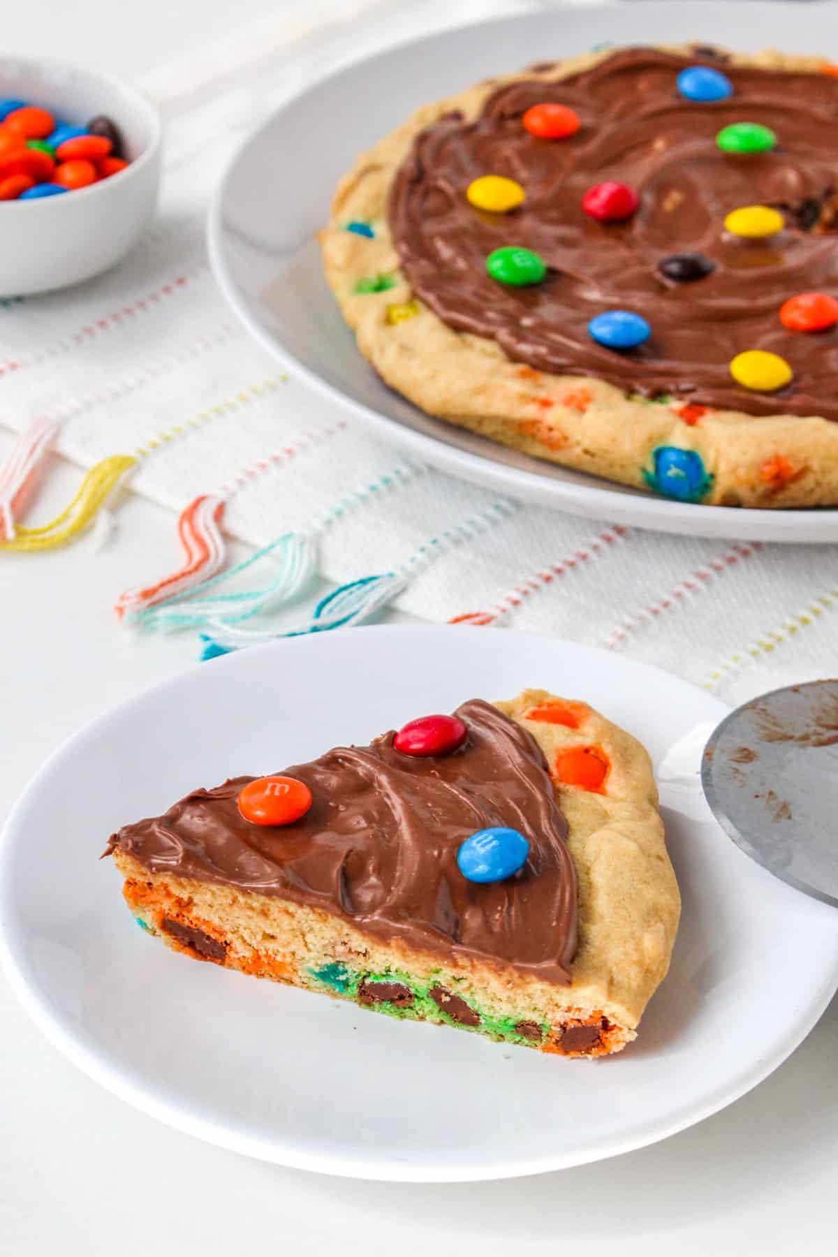 Triangular slice of skillet cookie pizza topped with M&Ms.
