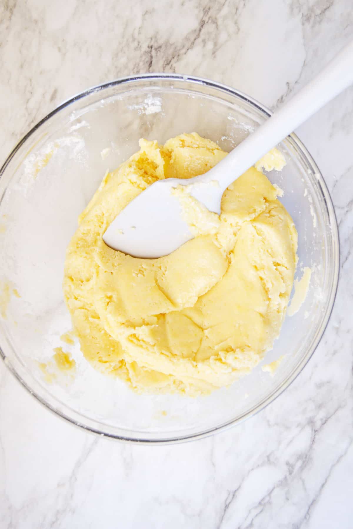 Cake mix cookie dough in glass mixing bowl with rubber spatula.