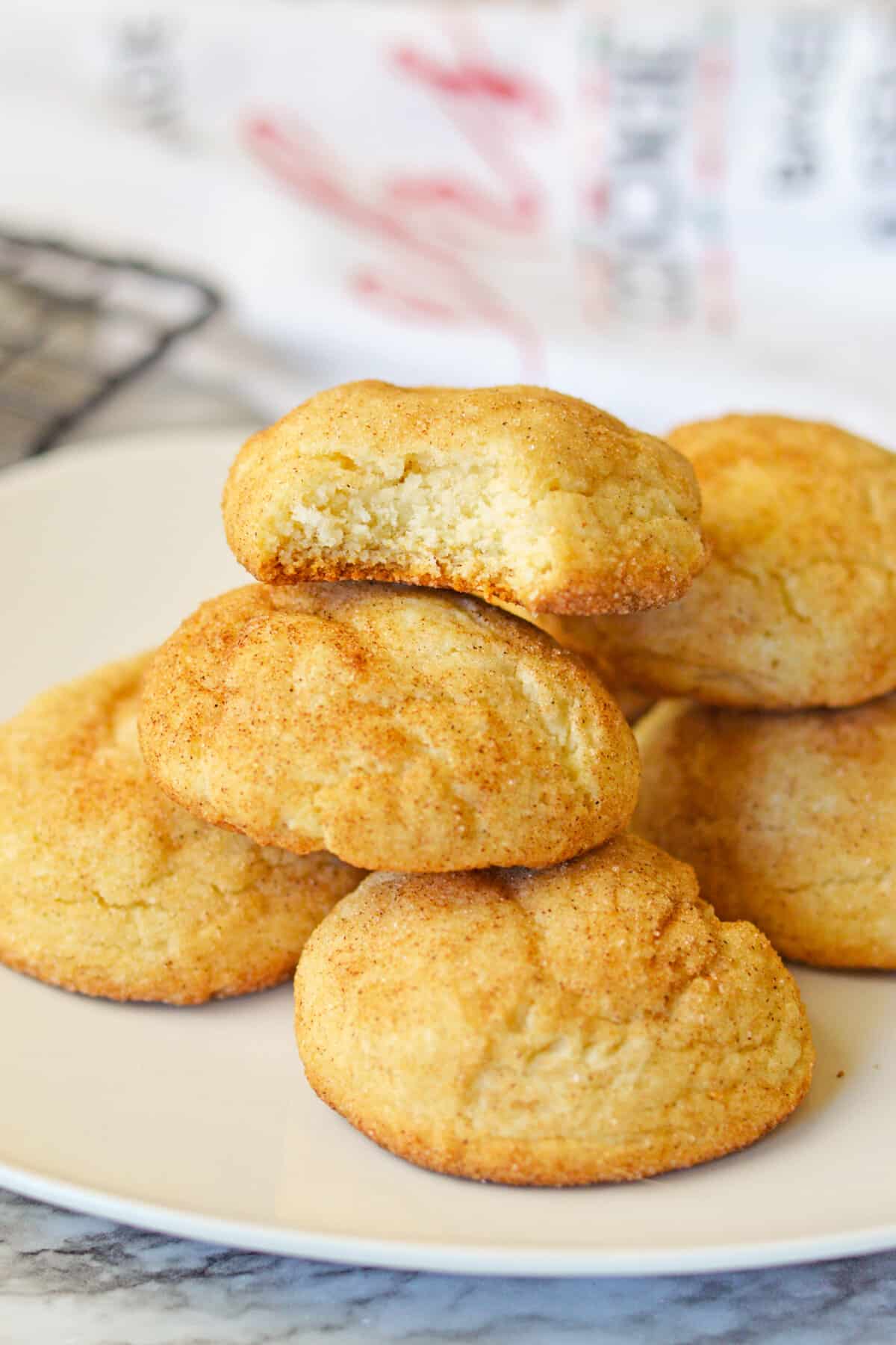 Cake mix snickerdoodles on a plate with one cookie missing a bite.