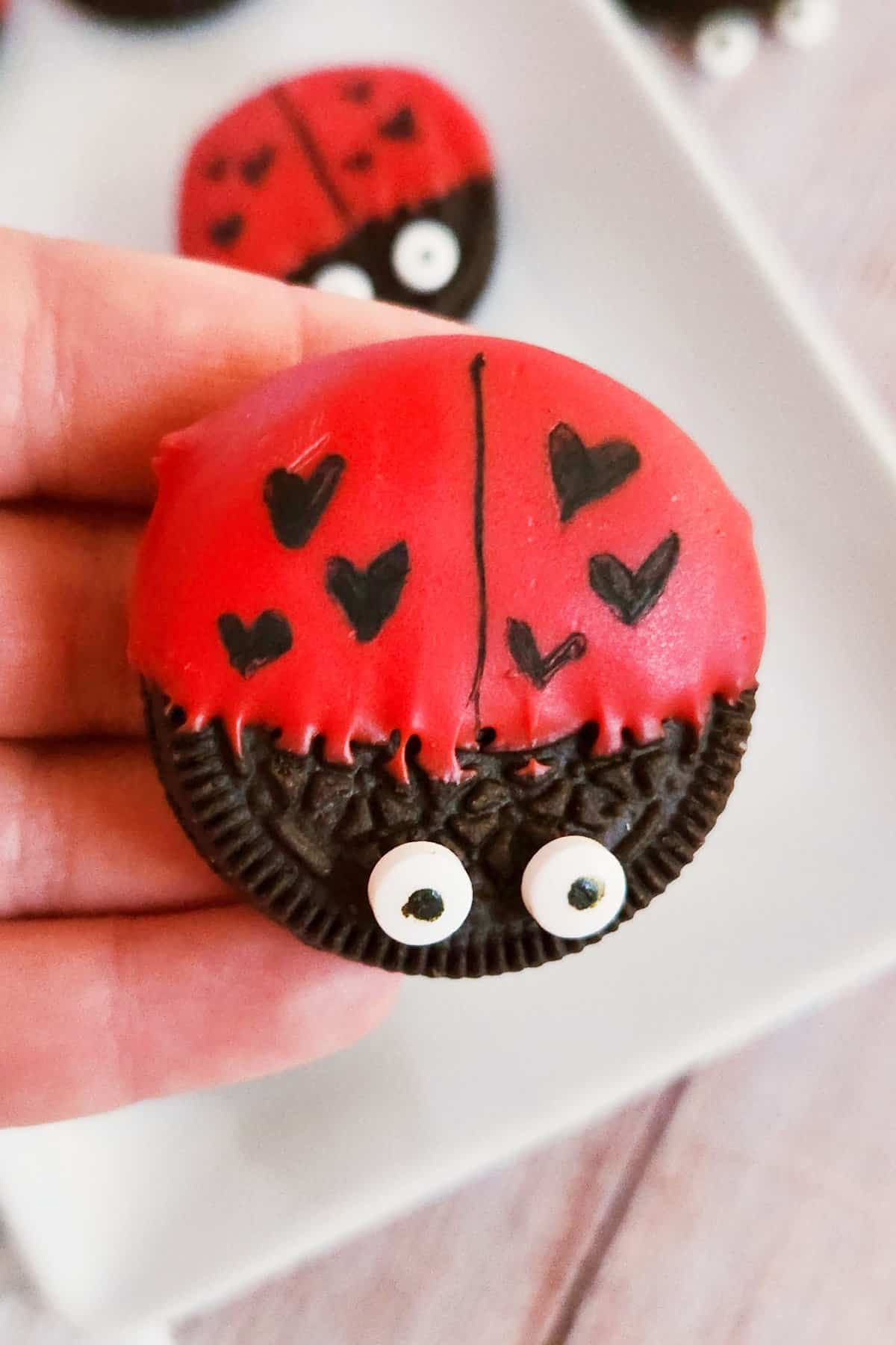 Hand holding a Valentine Oreo love bug.