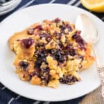 Serving of lemon blueberry dump cake scooped onto on a white plate with a silver spoon.