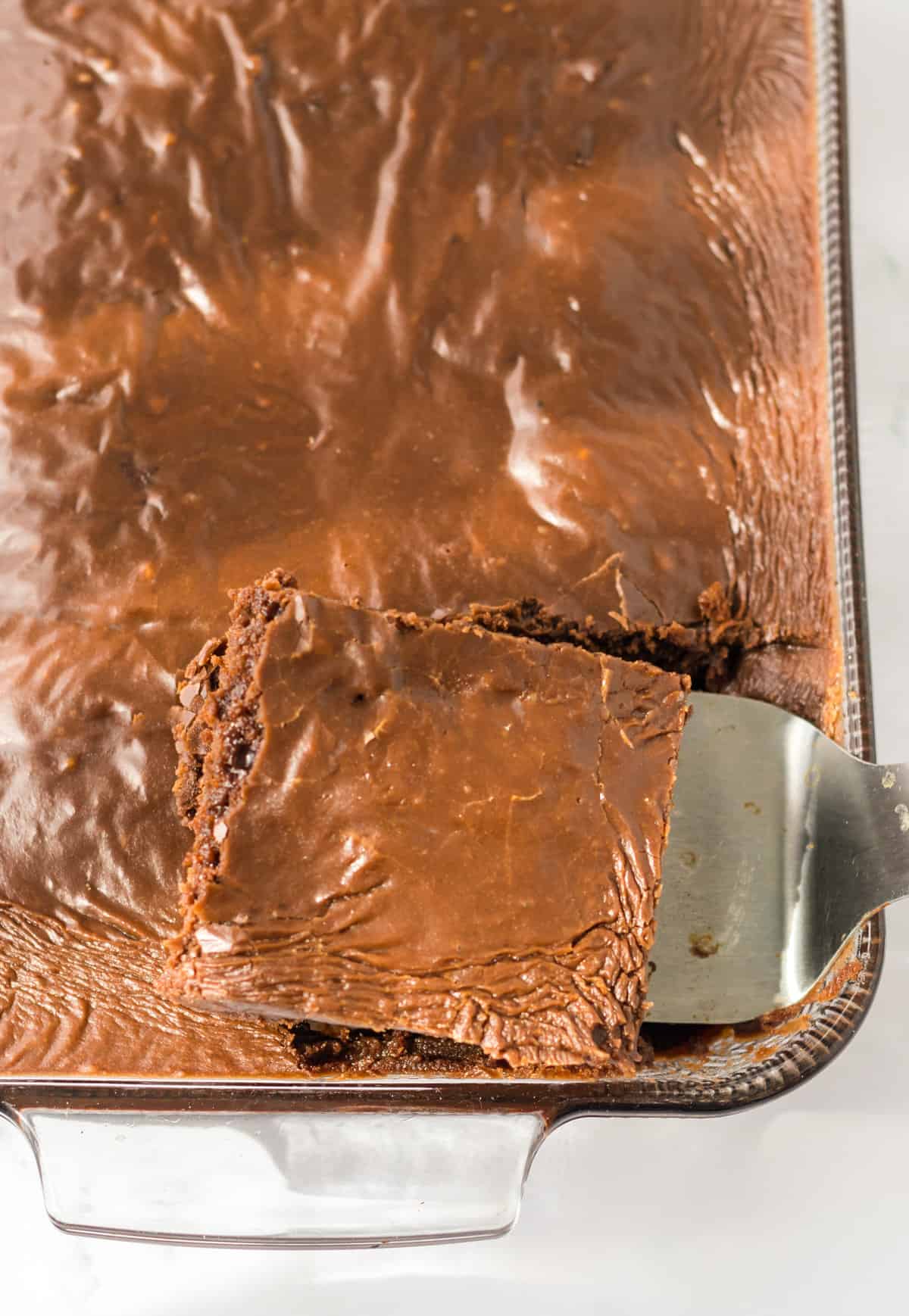 Spatula removing piece of chocolate cake with chocolate frosting.