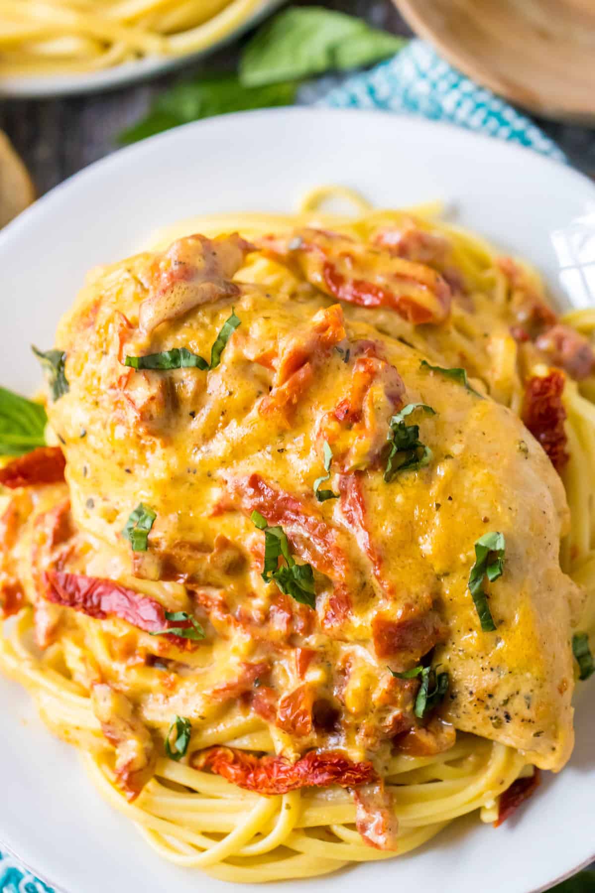 Slow Cooker Marry Me Chicken garnished with fresh basil and served over spaghetti.