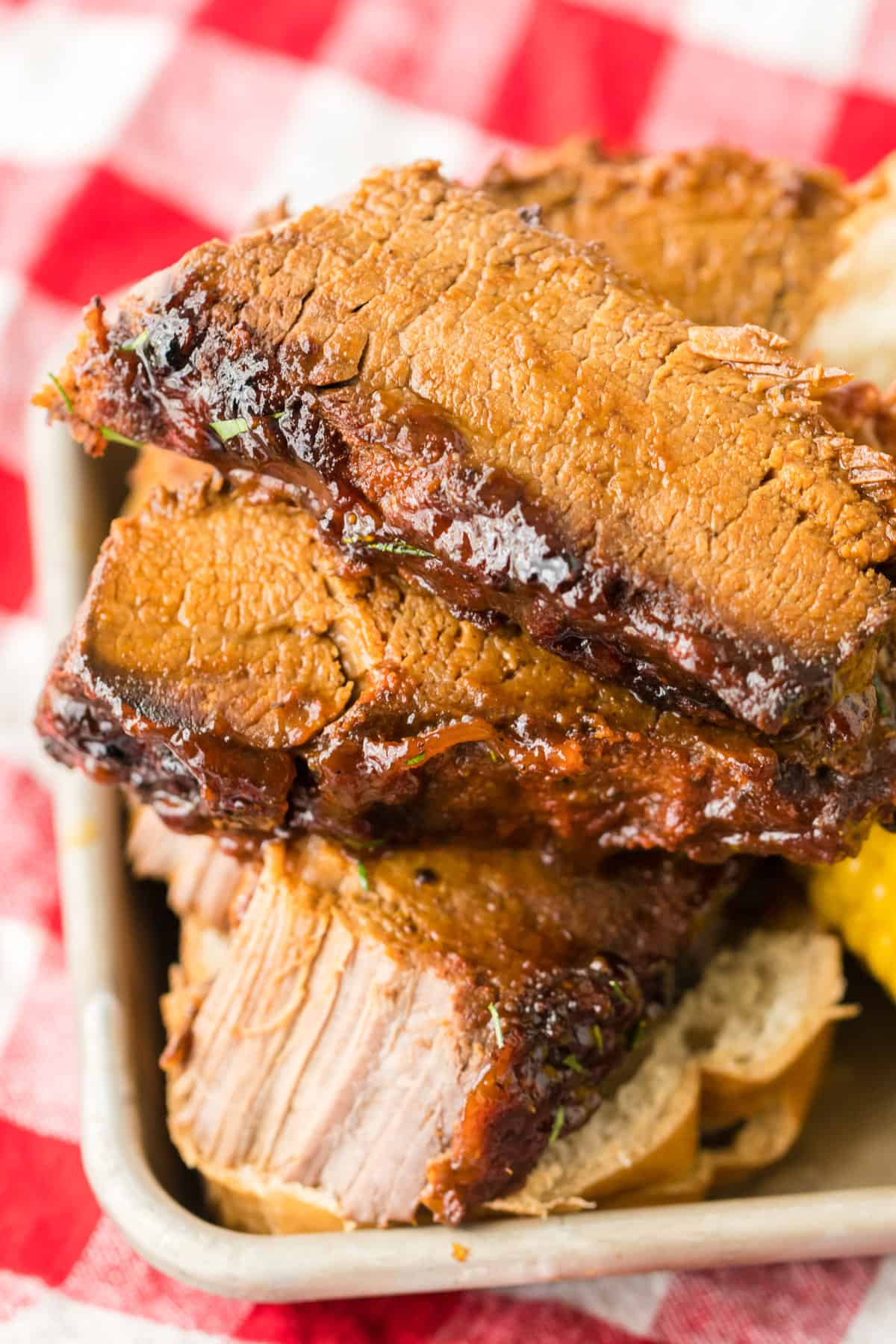 Slices of bbq slow cooked brisket served with corn and bread.