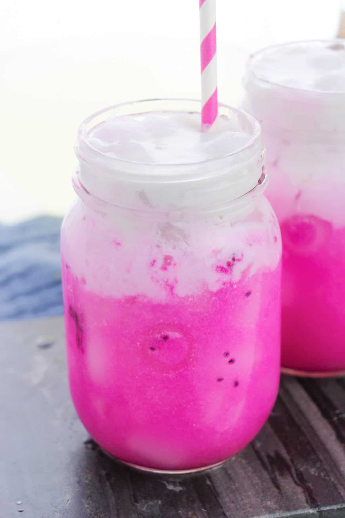 Copycat Starbucks Dragon Drink with vibrant pink mango dragonfruit refresher drink in mason jar topped with coconut milk.