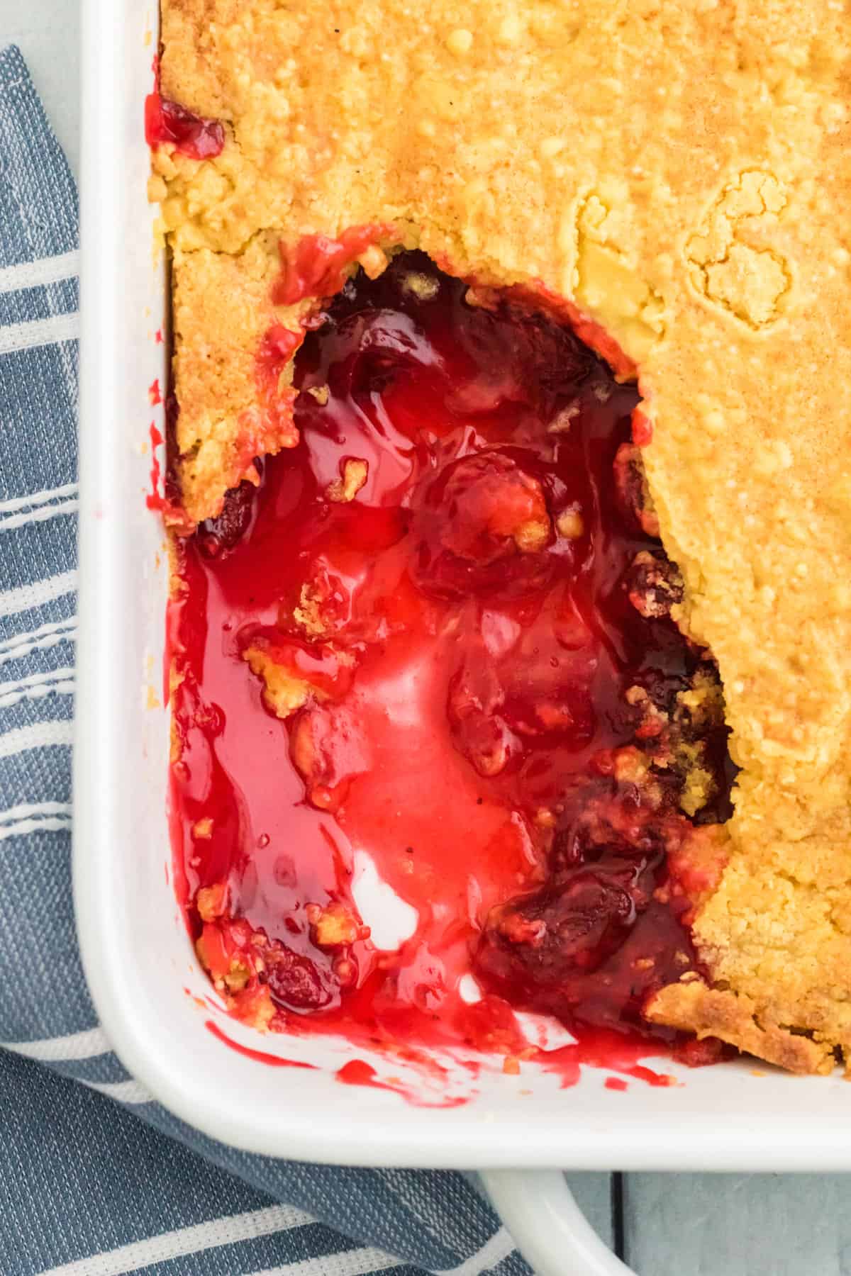 Top of dump cake with several scoops removed. You can see the strawberry filling beneath the cake layer.