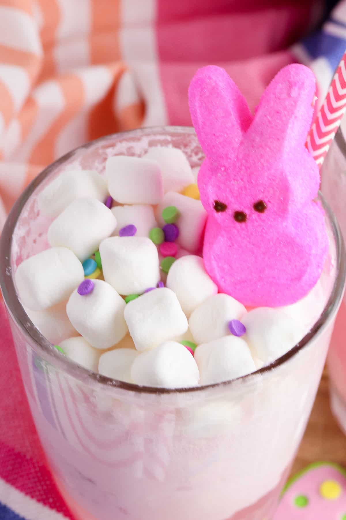 Glass of pink peeps punch topped with mini marshmallows, pink peeps bunny, and sprinkles.