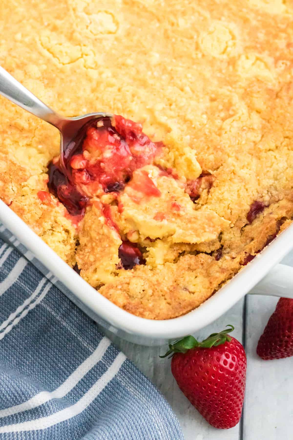 Large spoon breaking surface of dump cake and revealing the pie filling inside. 