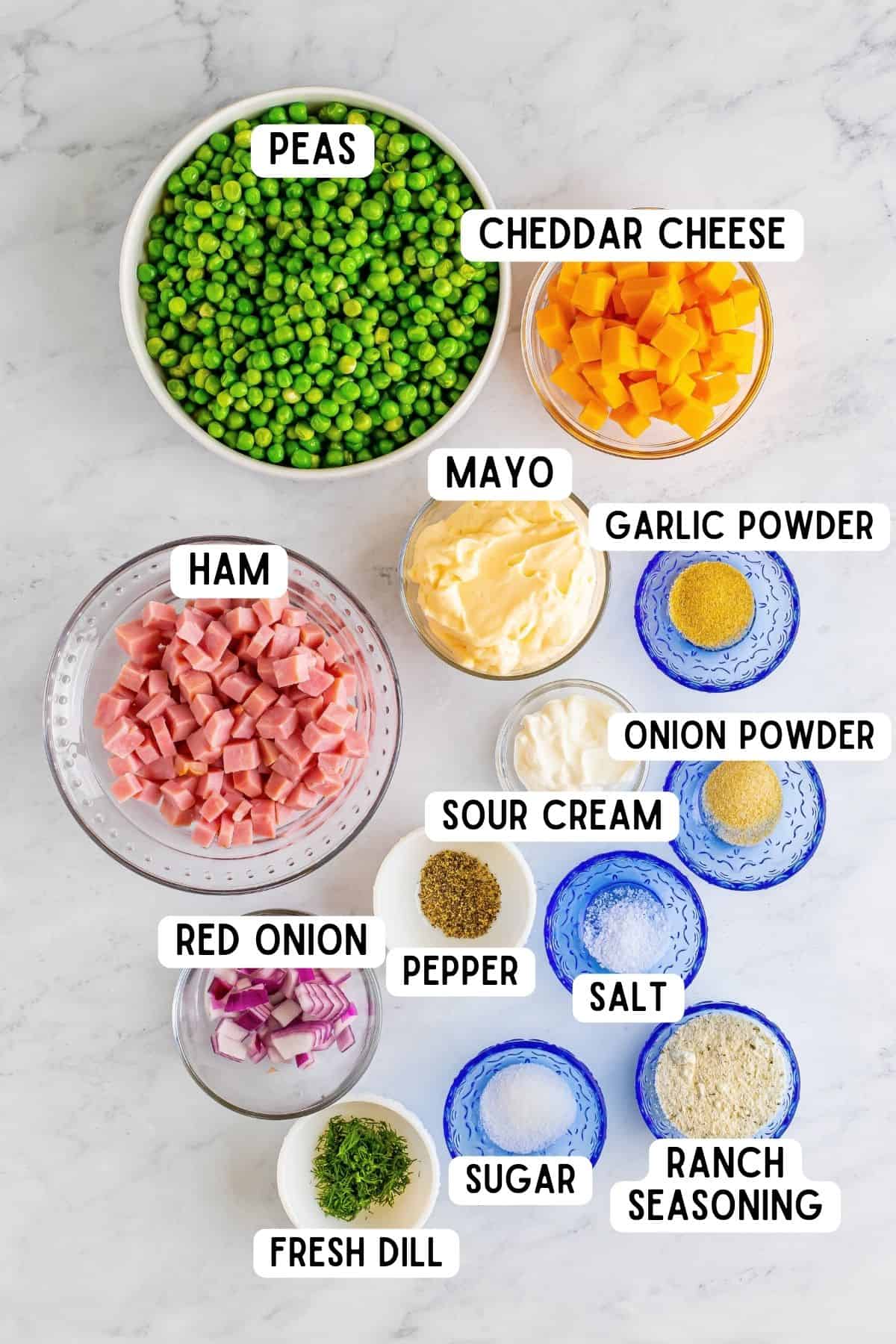 Ingredients in bowls, including: peas, cheddar cheese, ham, mayo, red onion, sour cream, onion powder, garlic powder, salt, pepper, ranch seasoning, and sugar.